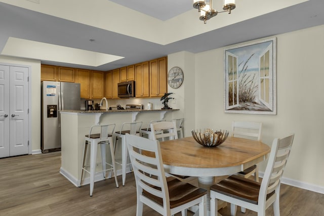 dining area with a raised ceiling and light hardwood / wood-style floors