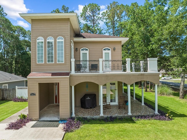 view of front of property featuring a patio area, a balcony, and a front yard