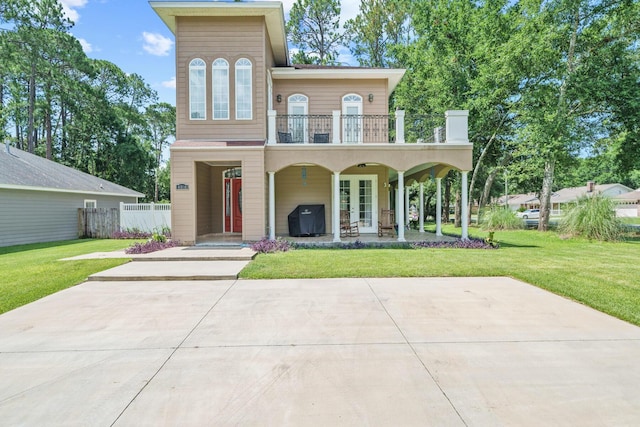 view of front of home with a front yard, french doors, and a balcony