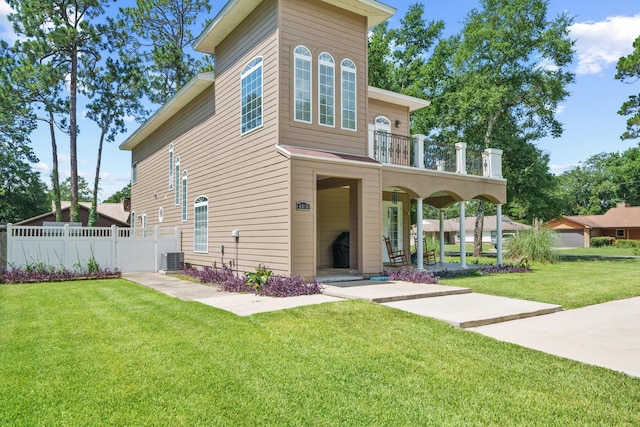 view of front facade with a balcony, central AC, and a front lawn