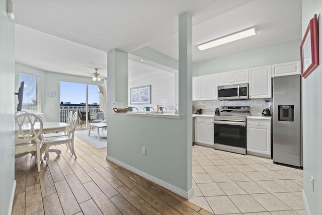 kitchen featuring appliances with stainless steel finishes, tasteful backsplash, ceiling fan, light hardwood / wood-style flooring, and white cabinetry