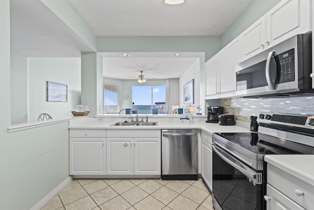 kitchen with decorative backsplash, stainless steel appliances, sink, light tile patterned floors, and white cabinetry