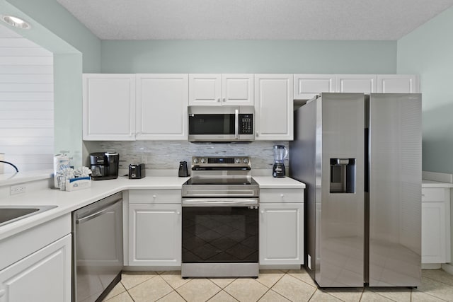 kitchen with a textured ceiling, light tile patterned flooring, white cabinetry, and stainless steel appliances