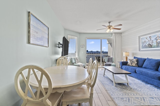 dining area featuring ceiling fan, wooden walls, and a textured ceiling