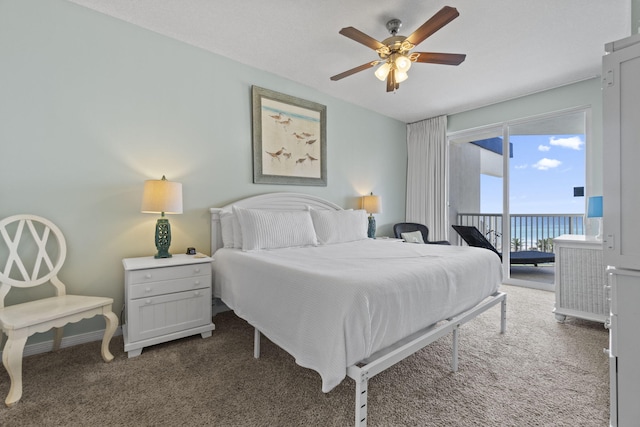 bedroom with access to outside, ceiling fan, a water view, and dark colored carpet