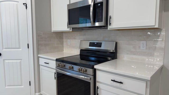 2718 Louis Cir, Crestview, FL 32536 - kitchen with white cabinets, appliances with stainless steel finishes, light stone counters, and backsplash