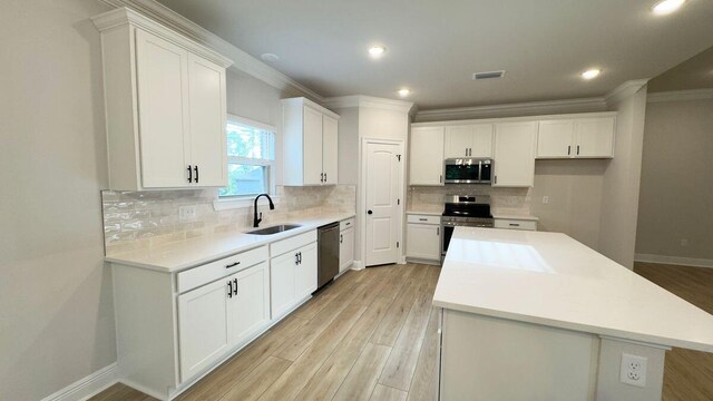 2718 Louis Cir, Crestview, FL 32536 - kitchen with a center island, a sink, crown molding, light wood-type flooring, and appliances with stainless steel finishes