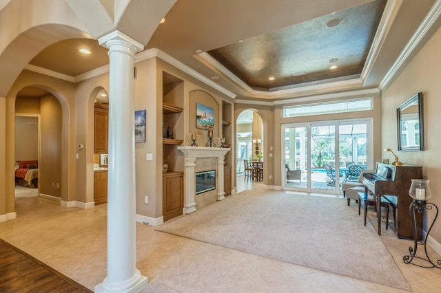 tiled living room featuring a tray ceiling, built in features, decorative columns, and crown molding