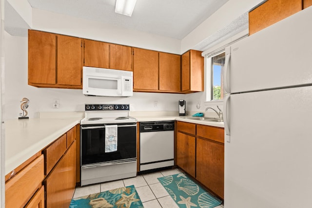 kitchen with sink, light tile patterned floors, and white appliances