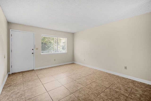 empty room with a textured ceiling and light tile patterned flooring