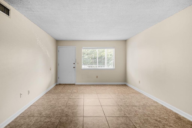 empty room featuring light tile patterned flooring and a textured ceiling