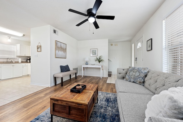 living room featuring ceiling fan, sink, and light hardwood / wood-style flooring