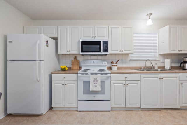 kitchen with sink, white appliances, white cabinetry, light tile patterned flooring, and decorative backsplash