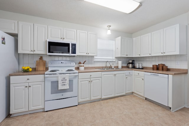 kitchen with backsplash, white appliances, sink, and white cabinets