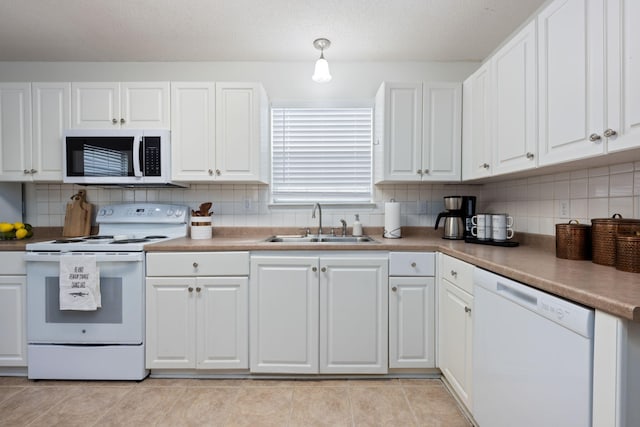 kitchen featuring tasteful backsplash, white cabinetry, sink, light tile patterned floors, and white appliances