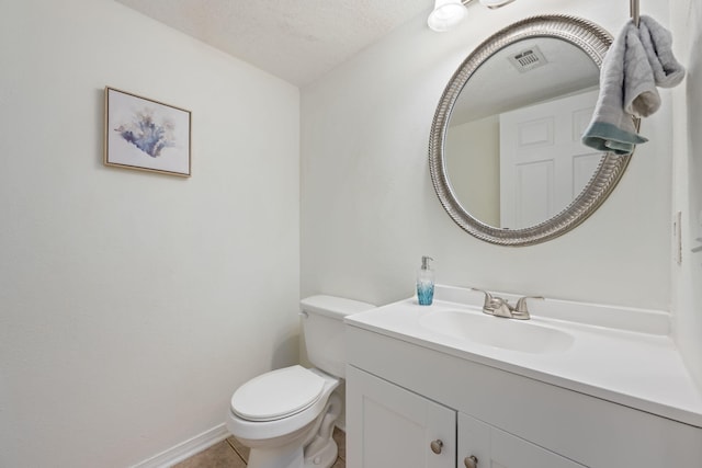 bathroom with tile patterned flooring, vanity, a textured ceiling, and toilet