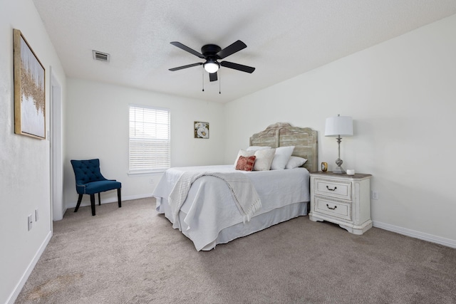 carpeted bedroom featuring ceiling fan and a textured ceiling