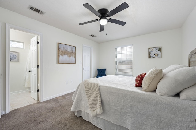 bedroom featuring ceiling fan, light colored carpet, and connected bathroom