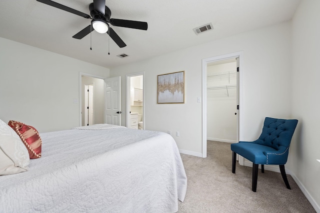 carpeted bedroom featuring ceiling fan, a walk in closet, ensuite bath, and a closet