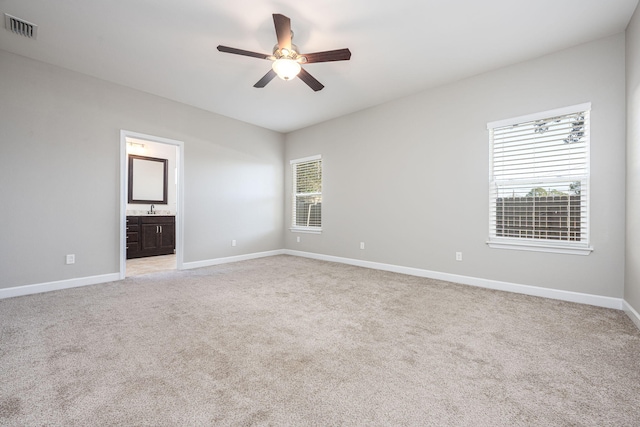 empty room featuring a wealth of natural light, ceiling fan, and light colored carpet