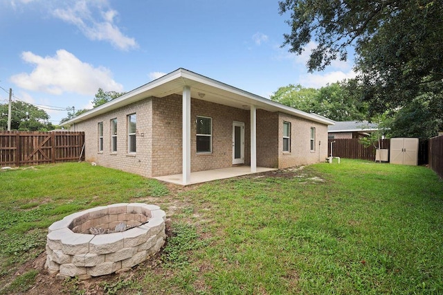 rear view of property with a fire pit, a shed, a yard, and a patio