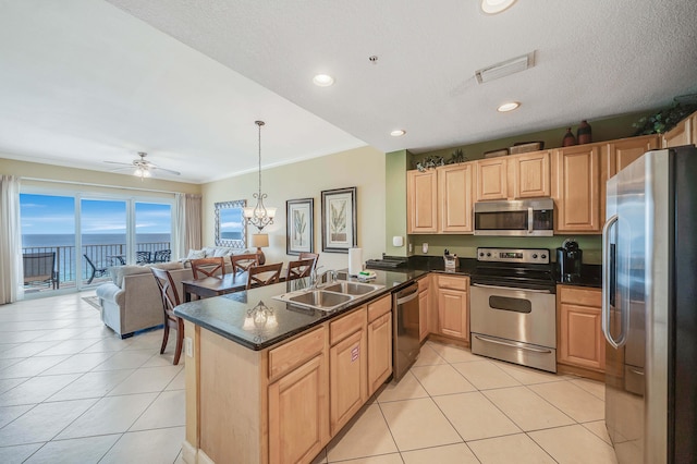 kitchen with kitchen peninsula, stainless steel appliances, sink, decorative light fixtures, and a water view