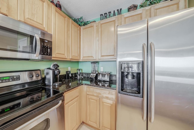 kitchen with light brown cabinets, dark stone countertops, a textured ceiling, and appliances with stainless steel finishes