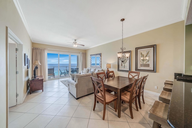 tiled dining area featuring crown molding, a water view, and ceiling fan with notable chandelier