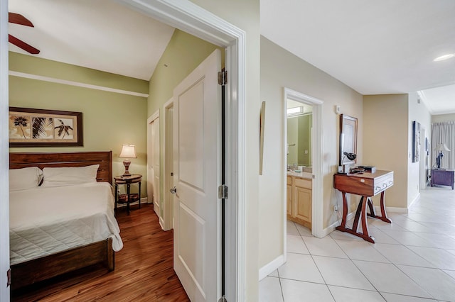 tiled bedroom featuring ensuite bath and ceiling fan