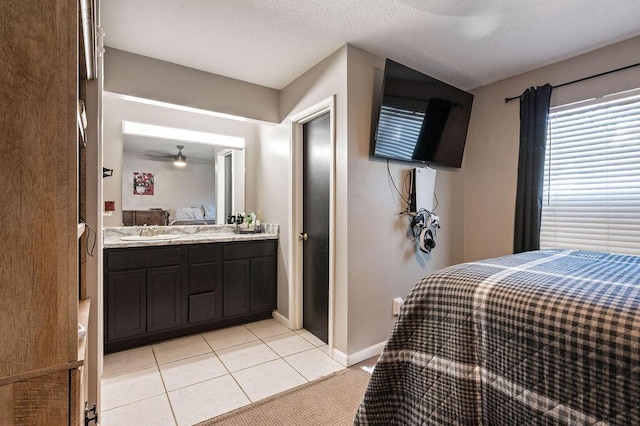 bedroom featuring light tile patterned floors, a sink, connected bathroom, and baseboards