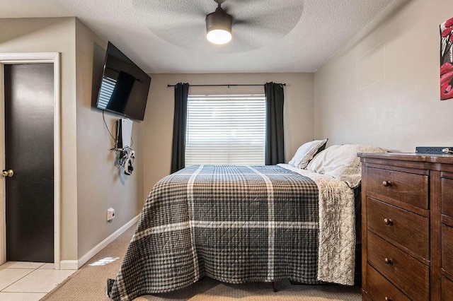 bedroom featuring a ceiling fan, light tile patterned floors, baseboards, and a textured ceiling