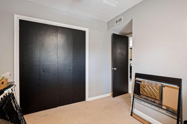 bedroom with a closet, light colored carpet, visible vents, and baseboards