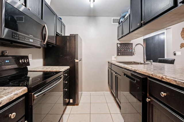 kitchen with light tile patterned floors, visible vents, a sink, dark cabinets, and black appliances