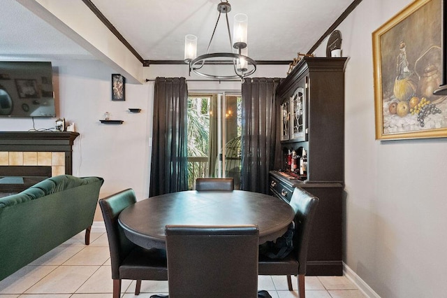 dining space with baseboards, a tiled fireplace, crown molding, a chandelier, and light tile patterned flooring