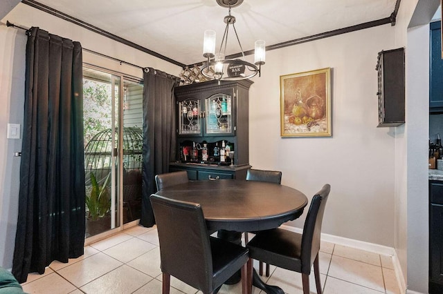 dining room featuring ornamental molding, light tile patterned floors, baseboards, and an inviting chandelier