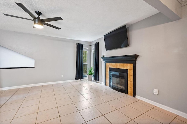 unfurnished living room featuring a textured ceiling, light tile patterned floors, a tiled fireplace, and baseboards