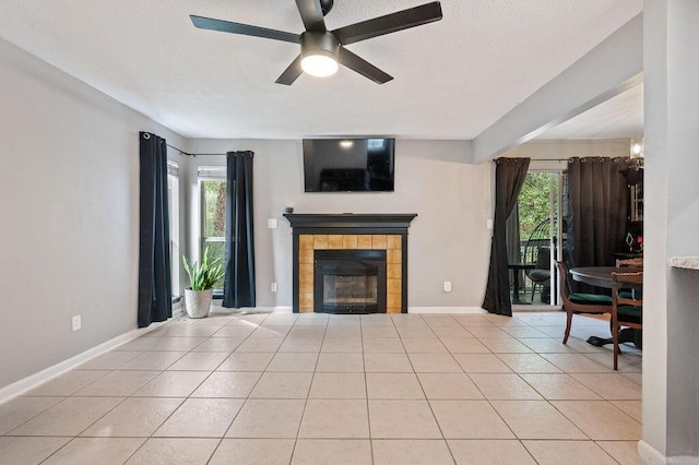 unfurnished living room with light tile patterned floors, plenty of natural light, a tile fireplace, and baseboards