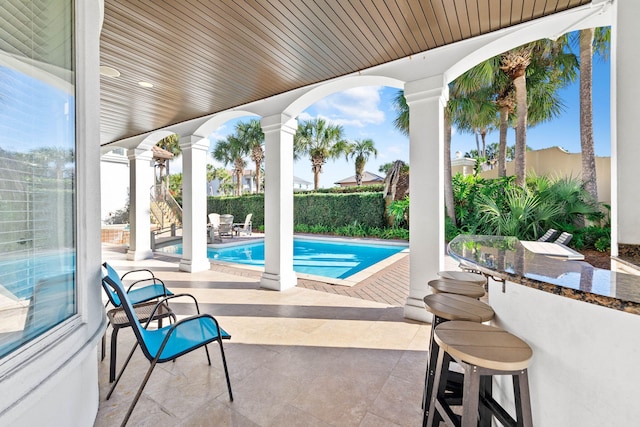 view of pool featuring exterior bar and a patio