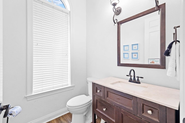 bathroom featuring wood-type flooring, vanity, toilet, and a healthy amount of sunlight