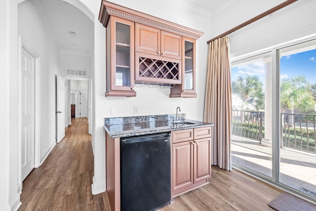 kitchen with ornamental molding, hardwood / wood-style flooring, dark stone counters, and sink