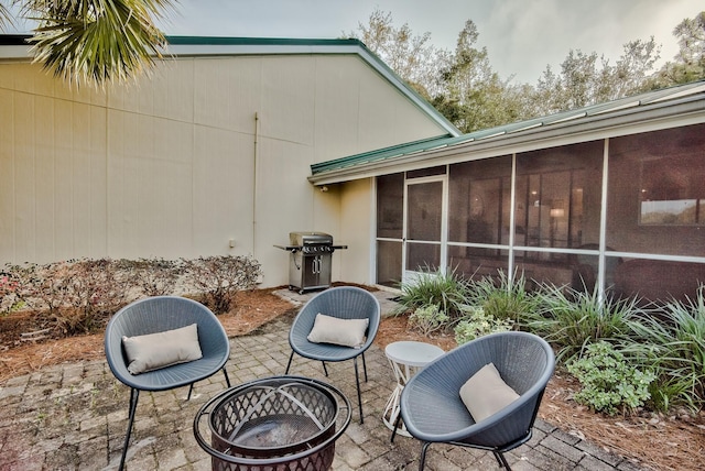 view of patio / terrace with area for grilling, a sunroom, and a fire pit