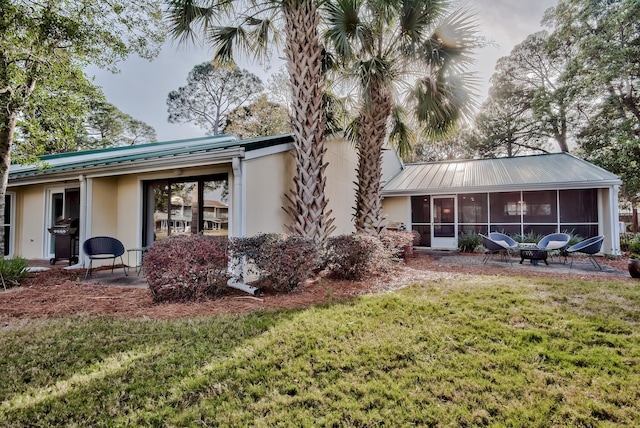 back of house featuring a sunroom, a patio, and a lawn