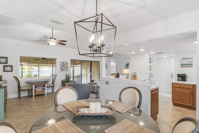 dining space with light tile patterned floors and ceiling fan with notable chandelier