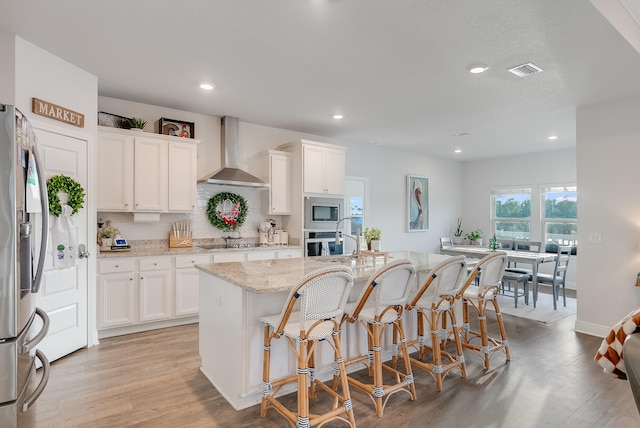 kitchen featuring white cabinets, appliances with stainless steel finishes, and wall chimney range hood