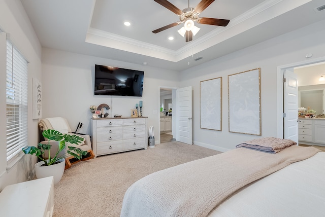 bedroom featuring ceiling fan, ornamental molding, connected bathroom, a tray ceiling, and light colored carpet