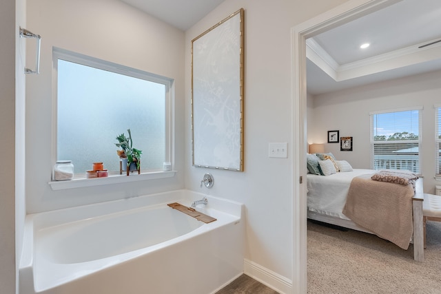 bathroom with a raised ceiling, a bathtub, and ornamental molding