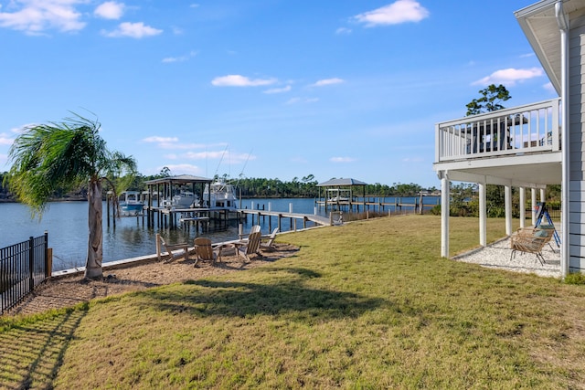 view of dock with a yard, a water view, and an outdoor fire pit