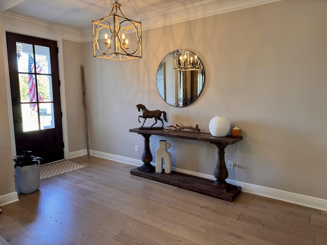 foyer entrance featuring a notable chandelier, wood-type flooring, and crown molding