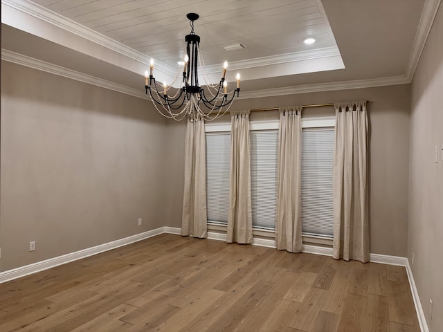 spare room with a chandelier, baseboards, ornamental molding, light wood-type flooring, and a tray ceiling