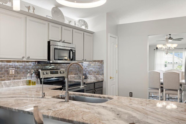 kitchen featuring sink, gray cabinets, tasteful backsplash, light stone counters, and stainless steel appliances